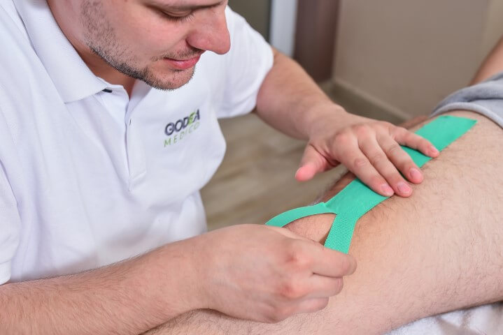 Terapeut Godea Medico lepi kinezio traku na koleno pacijenta